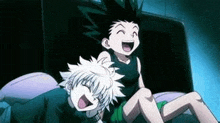 two anime characters , gon and killua , are laughing while sitting on a bed .