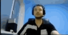 a man wearing headphones and a headset is sitting in front of a computer .