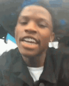 a close up of a man 's face with his mouth open and a white shirt on .
