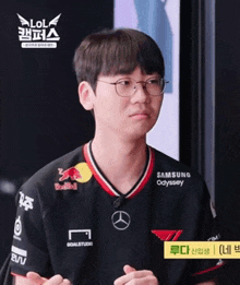 a man wearing glasses and a samsung odyssey shirt looks at the camera