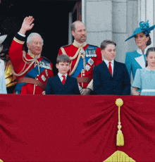 a group of people standing on a balcony including a man in a red uniform