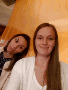 two women are posing for a picture and one is wearing earrings