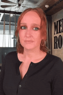 a woman with red hair is standing in front of a sign that says me rock