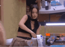 a woman in a black crop top is standing in front of a table