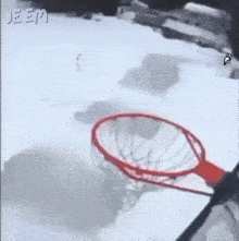 a person is playing basketball in the snow with a hoop .