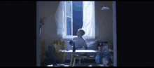 a man is sitting at a table in front of a window in a living room .