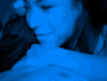 a close up of a woman 's face with a blue light behind her