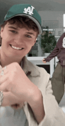 a man wearing a la hat is smiling and giving a fist bump