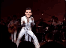 a man in a white suit is dancing on stage in front of a band