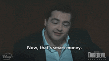 a man says " now that 's smart money " in front of a daredevil poster