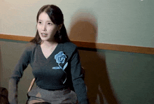 a woman wearing a grey sweater with a blue flower on the front sits in a chair