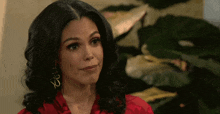 a woman wearing a red shirt and gold earrings with the letter b on them