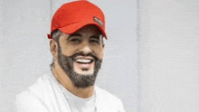 a man with a beard wearing a red hat is smiling .