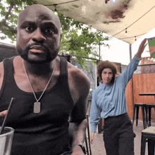 a man in a black tank top and a woman in a blue shirt are standing next to each other