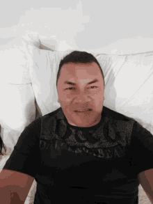 a man wearing a black shirt that says dolce & gabbana is laying on a bed