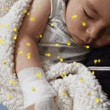 a baby with a bandage on his arm is sleeping on a blanket
