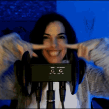 a woman wearing headphones is smiling and covering her ears with her fingers