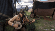 a man in a cowboy hat is playing a banjo in front of a tent with gifrun.com written below him