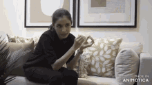 a woman is sitting on a couch with made in animatica written on the bottom of the screen