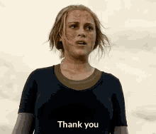 a woman with a dirty face is standing in front of a cloudy sky and saying `` thank you '' .