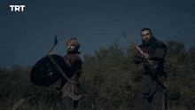 a man in a black jacket is holding a bow and arrow in his hand .