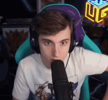 a young man wearing headphones and a white t-shirt is sitting in front of a microphone in a chair .