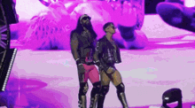 two wrestlers are standing next to each other on a stage .