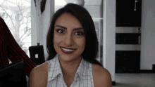 a woman wearing red lipstick and a white shirt smiles