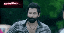 a man with a beard is wearing a plaid shirt and necklace