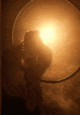 a woman is standing in a hoop in a dark room with the sun shining through it