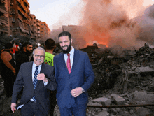 two men standing in front of a burning building with a man wearing a yellow shirt that says ' rescue ' on it
