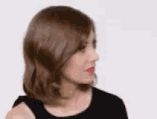 a woman with brown hair and red lipstick is wearing a black dress and looking to the side .