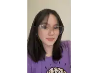 a young woman wearing glasses and a purple shirt is looking at the camera .