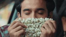 a man is holding a bunch of popcorn in front of his nose