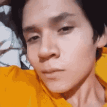 a close up of a person 's face in a yellow shirt .