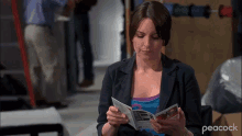 a woman is reading a pamphlet with peacock written on the bottom