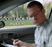 a man sitting in a car writing on a piece of paper with the words " good luck the puff " above him