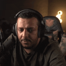 a man wearing headphones and a watch is covering his face with his hands