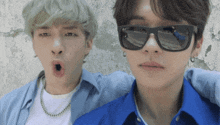 two young men wearing sunglasses and blue shirts are posing for a picture