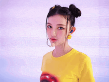 a woman wearing a yellow t-shirt with a mouth painted on it stands in front of a purple background