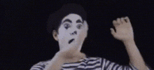 a man wearing a mime mask is making a funny face with his hands .