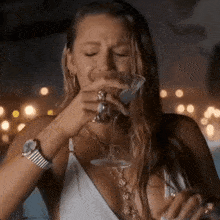 a woman in a white dress is drinking a martini with her eyes closed