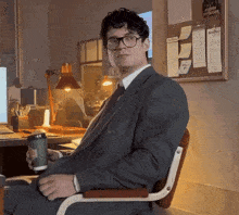 a man in a suit and tie is sitting in a chair holding a coffee cup