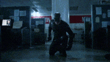 a man in a black hoodie is standing in a dark room holding a knife