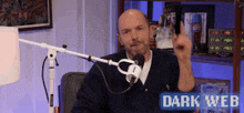 a man giving a middle finger in front of a microphone with the words dark web written on the bottom
