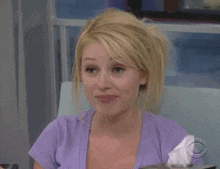 a woman in a purple shirt is sitting in a chair with a box of tissues in front of her .