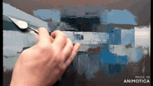 a hand is holding a spatula over a painting with the words made in animotica below it