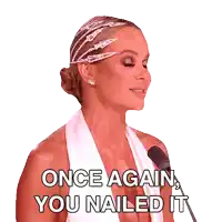 a woman in a white dress speaking into a microphone with the words once again you nailed it below her