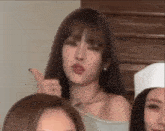 a group of women are standing next to each other in a room and one of them is pointing at the camera .