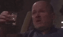 a bald man is drinking from a bottle with a label that says ' pilsner ' on it